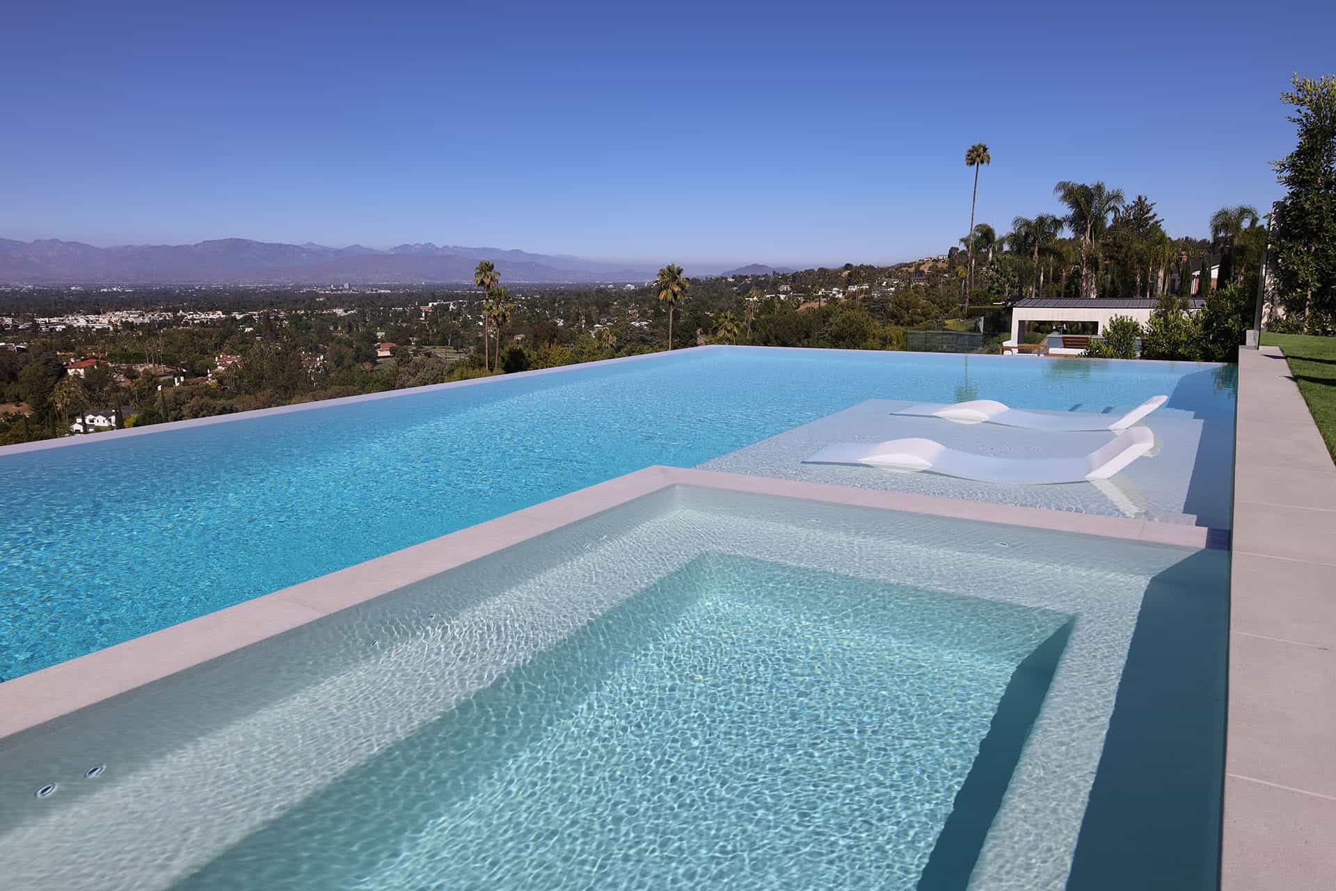 Infinity-edge pool with a tanning ledge and in-water loungers, valley view